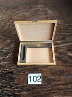 Square in open wood case with lot number visible