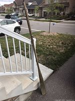 Full view of weathered wooden oar leaning against stair railing