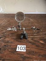 Front view of stand showing magnifier, two clamps, cast iron base