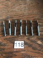 Seven vintage metal leather punches laid out on wooden surface