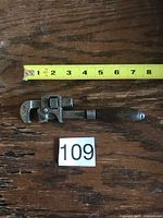 Full view of 7" Stillson adjustable wrench beside measuring tape confirming length