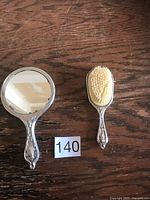Hand mirror and brush set displayed on wooden surface