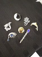 Group shot showing all seven brooches with clear view of designs and finishes