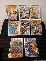 Front covers of eight Fantastic Four comic issues displayed on black surface, each bagged and boarded.