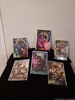 Front view of six bagged and boarded Grimm Fairy Tales comic books displayed on black surface
