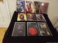 All four comic books in protective bags with six art prints laid out