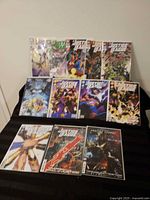 All twelve Justice League comics displayed on black cloth