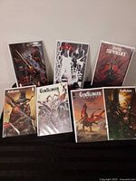 Front view of all seven bagged and boarded comics standing and lying on table