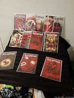 Twelve Red Mother comic books laid out, showing cover art and protective bags