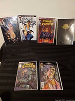 Group shot of five bagged Tomb Raider comics standing and lying on black cloth