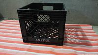 Front view of black plastic milk crate showing lattice sides, handle cutout and 40/11 marking