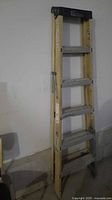 Full view of folded 6-ft ladder leaning against wall
