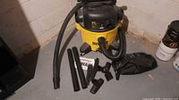 Vacuum canister, hose, two wands, four attachments, accessory bag displayed on floor