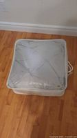 Front view of grey comforter folded inside clear plastic front storage bag