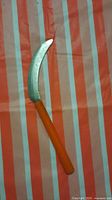 Hand sickle laid flat showing full length and handle color