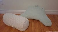 Light blue backrest pillow and white bolster pillow on floor
