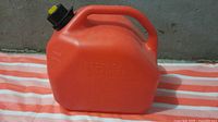 Front view of red plastic 10 L jerry can showing handle and cap