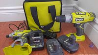 Complete set displayed: drill, impact driver, charger, two batteries, bag, belt clip