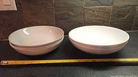Side view showing stack of three 8-inch bowls beside two 9-inch bowls with tape measure for scale