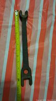 Full view of wrench next to tape showing length