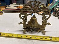 Front view of brass dragon table bell with measuring tape showing height