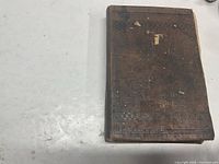 Front cover of brown cloth cookbook showing heavy wear