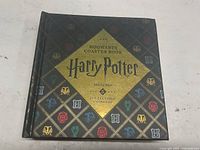 Front cover of Hogwarts Coaster Book showing title and crests