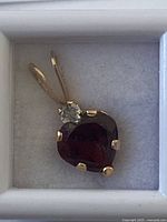 Front close-up of pendant showing garnet, diamond, prongs and bail