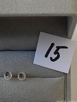 Open jewelry box showing pair of tanzanite stud earrings and lot number