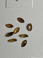 Eight marquise-cut orange tourmalines laid out on white background