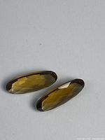 Two elongated oval champagne citrine gemstones on neutral background