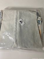 Jeans folded in clear plastic, size label 30 not visible but referenced