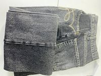 Folded charcoal stone-washed jeans showing leg fabric texture