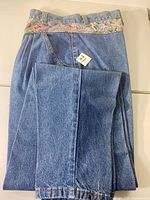 Full view of jeans front, shows denim color and floral waistband