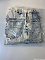 Shorts folded in clear plastic bag showing back pocket and chain