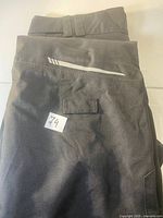Front view of folded black Sunice Stormpack pants