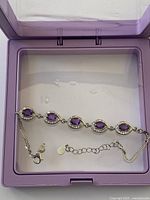 Bracelet displayed in box showing five amethyst links and chains