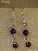 Front view of both sterling silver dangle earrings with garnet beads
