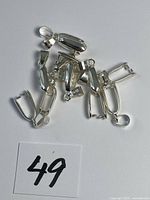 Pile of sterling silver bails numbered 49 on white background