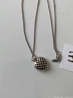 Necklace laid flat showing locket front and chain with clasp