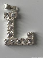 Front view of silver letter L pendant with stones