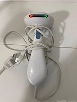 Full view of white Conair handheld steamer, cord coiled