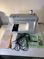 Front view of Kenmore sewing machine with foot pedal, manuals, cords and accessories laid out