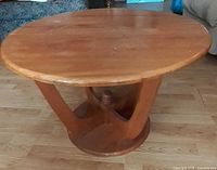 Round pine coffee table showing top, curved supports, lower round base