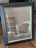 Front view of rectangular mirror showing black frame, inner silver border, and reflective surface