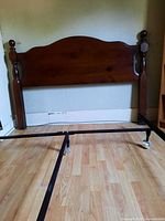 Wood queen headboard with metal frame rails displayed on floor