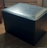Black vinyl rectangular footstool, closed lid visible
