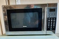 Front view of Kenmore stainless steel microwave showing control panel, door, and overall condition