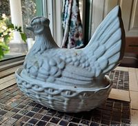 Angled view of white bisque hen on nest covered dish showing lid and base