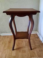 Full view of the dark wood occasional table showing top, legs, and lower shelf